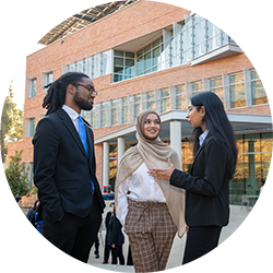 Three School of Business students chatting in front of the new School of Business building
