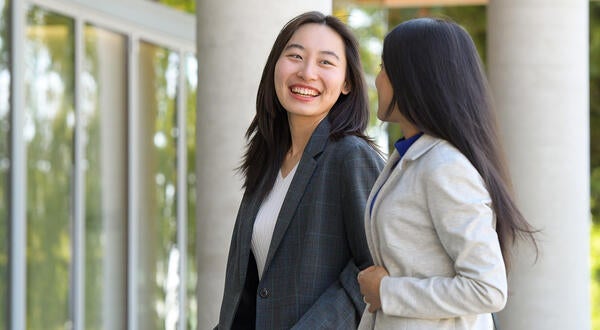 Two female graduate students in front of new building