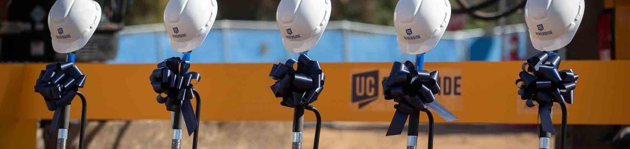 5 shovels with bows and helmet, groundbreaking at UC Riverside