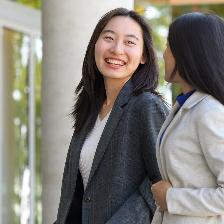Two female graduate students in front of new building