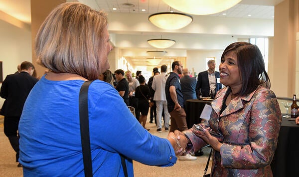 Two People Shaking Hands at Economic Forecasting Conference