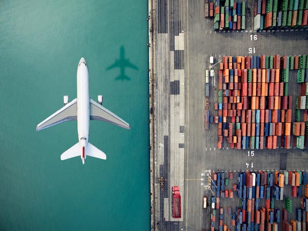 aerial view of airplane flying over water and shipyard