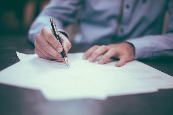 man's hand and arms, writing on paper (c) unsplash