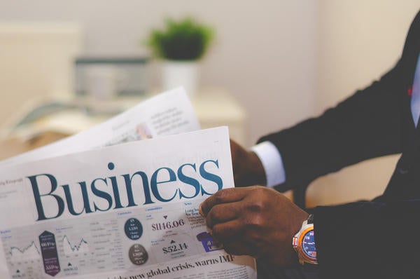 man's arms and hands holding business newspaper (c) unsplash