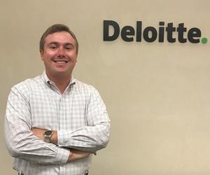 Turner Stanton standing in front of Deloitte logo