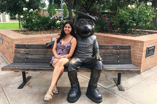 Anjali Kansara sitting next to UCR's mascot, Scotty the Bear