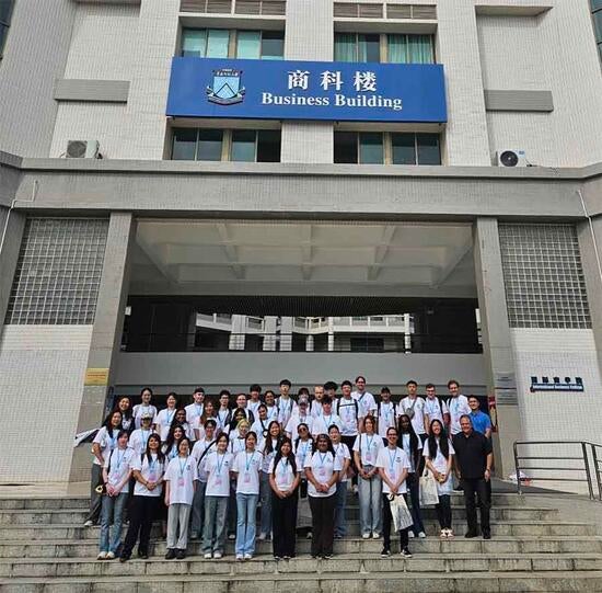 Business students posing on the stairs in front of the university's Business Building