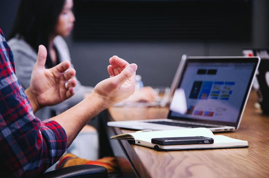 laptop on table, man's hands gesturing (c) unsplash