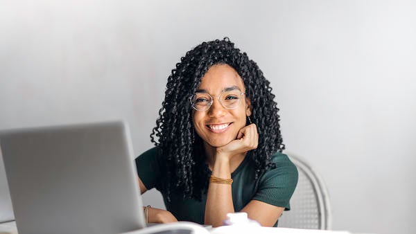 ABLE young woman smiling, sitting at laptop, chin on hand young woman smiling, sitting at laptop, chin on hand